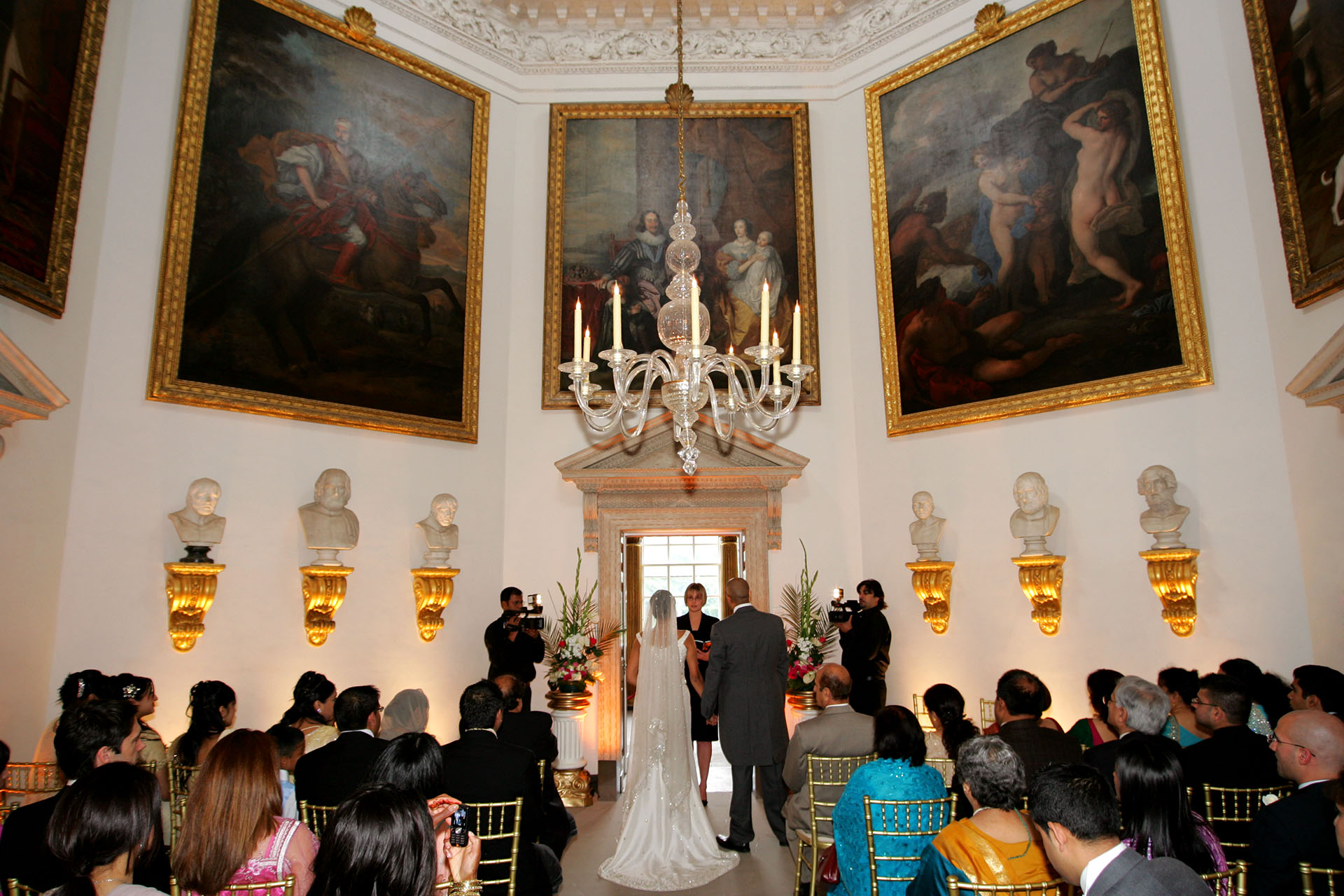 Asian and Indian wedding ceremony inside Chiswick House London with guests seated beneath historic paintings.